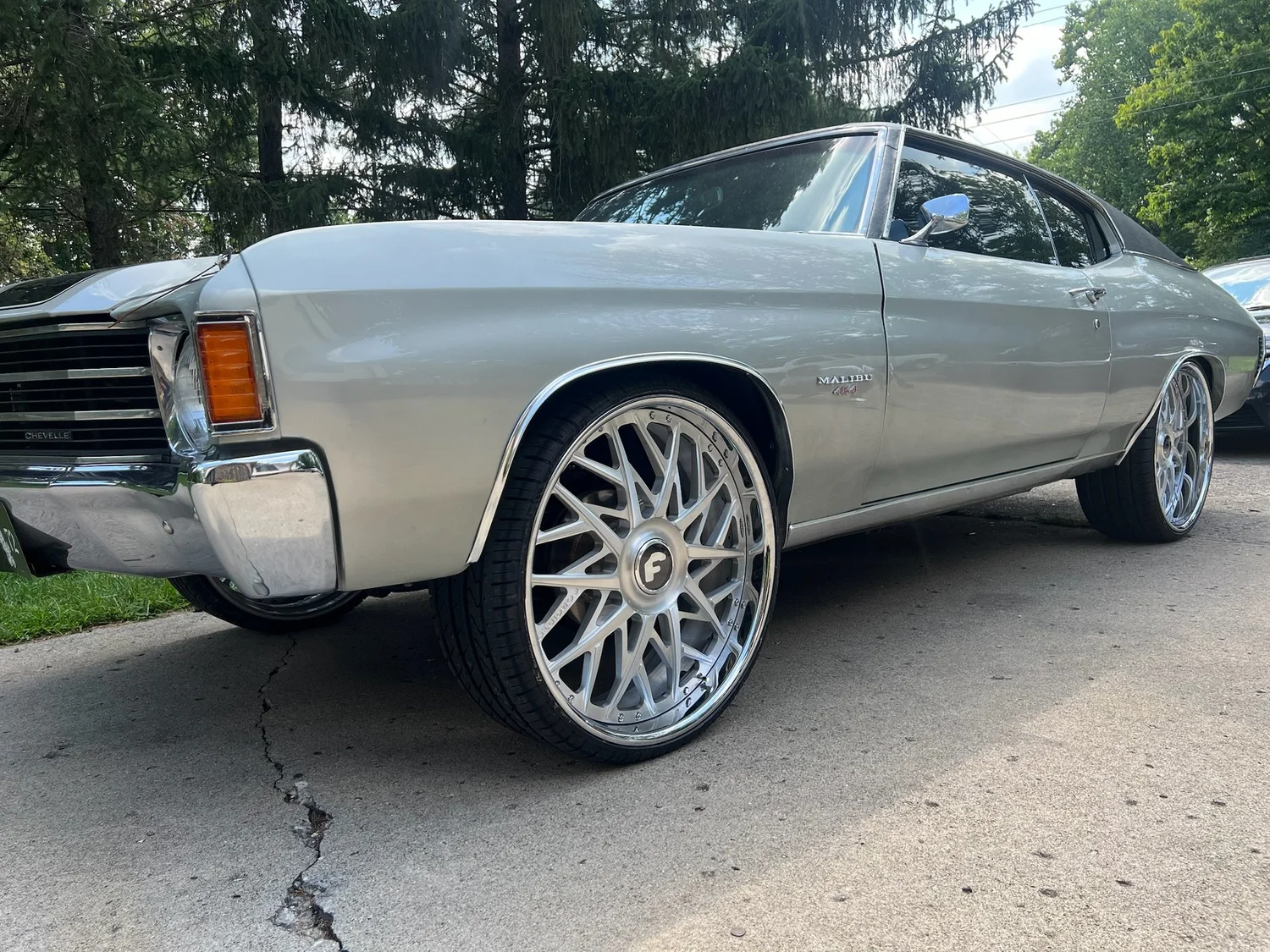 Gray 1972 Chevelle Malibu on polished multi-spoke wheels, parked on a shaded driveway