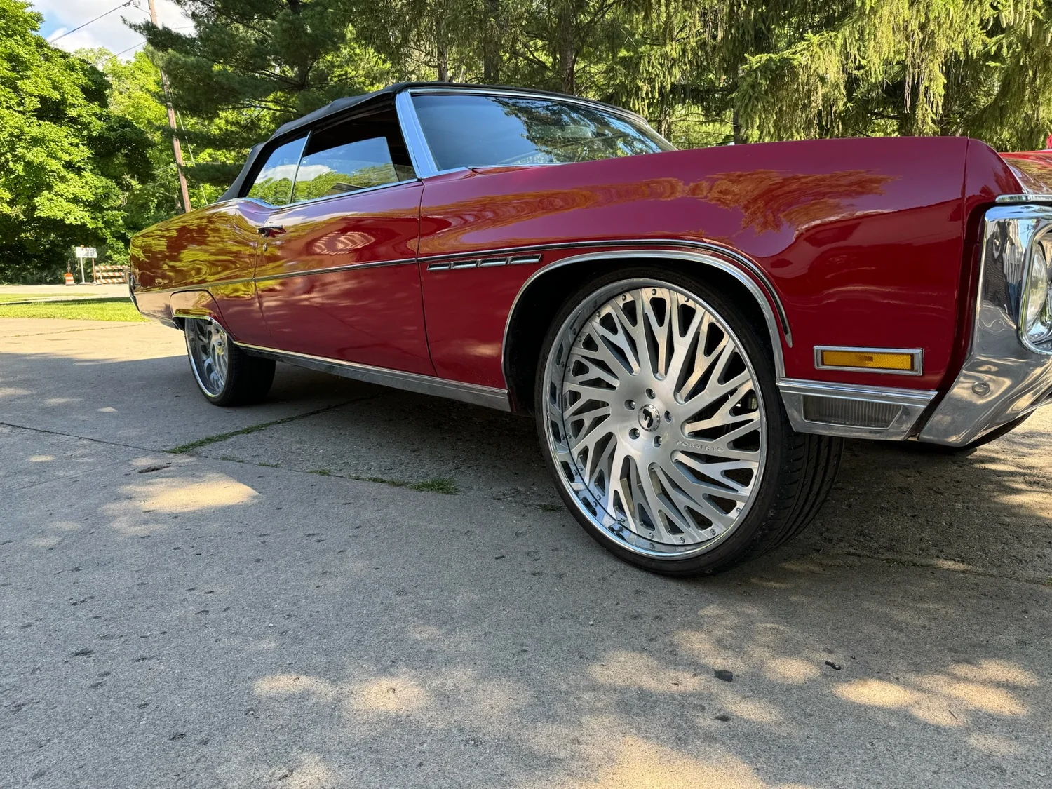 Red convertible with the top up, shot low across a polished front wheel
